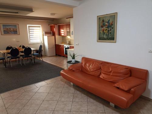 a living room with a brown couch and a kitchen at ROYAL Apartmani in Bosanski Šamac