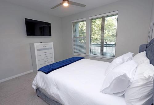 a bedroom with a white bed with a ceiling fan at Comfortable Getaway Downtown Htx in Houston