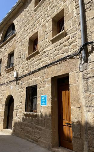 a stone building with a brown door and a blue sign at Casa Nostra Matarranya in Calaceite