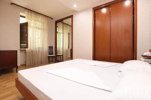 um quarto com uma cama branca e uma porta de madeira em AM Apartments 5 em Yerevan