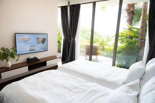 1 dormitorio con 2 camas blancas y TV en 1BR, 1 Sofa bed Luxurious 5-stars Flamingo Resort., en Phúc Yên