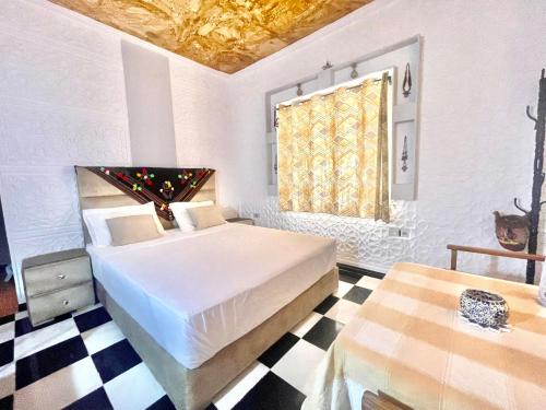 a bedroom with a bed and a checkered floor at La Maison Traditionnelle Hôtel et guesthouse in Tafraoute
