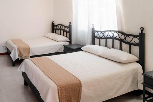 a bedroom with two beds and a window at Marqués Oaxaca - Hotel in Oaxaca City