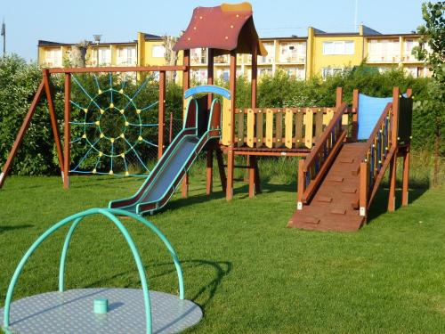 a playground with a slide in the grass at Silver Bursztynowe Komnaty in Darłówko