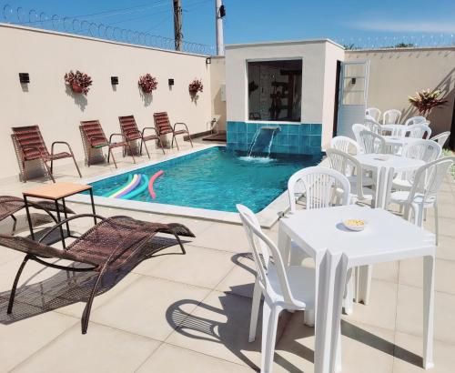 a patio with tables and chairs and a swimming pool at Império D in Tanabi