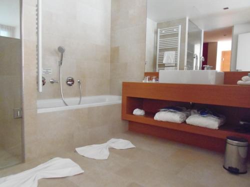 ein Bad mit einem Waschbecken, einer Dusche und Handtüchern in der Unterkunft Apartments Spa Resort Styria- ADULTS ONLY in Bad Waltersdorf