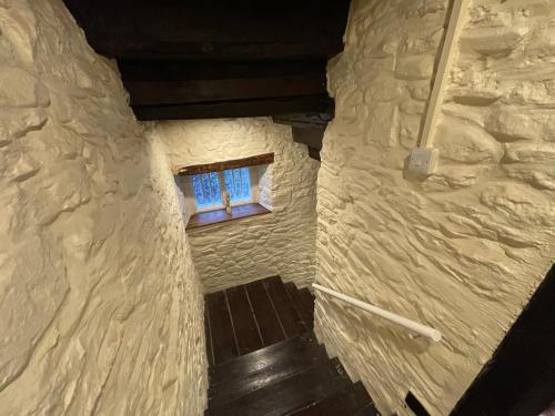 a small window in a stone building with a staircase at Large Historic Farmhouse in Rhondda Valley Perfect for Groups with Hot Tub in Blaencwm