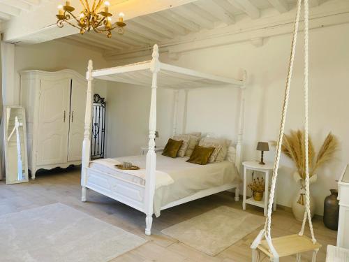 sypialnia z białym łóżkiem z baldachimem i żyrandolem w obiekcie LE SAINT LEONARD w mieście Montceaux-lès-Provins