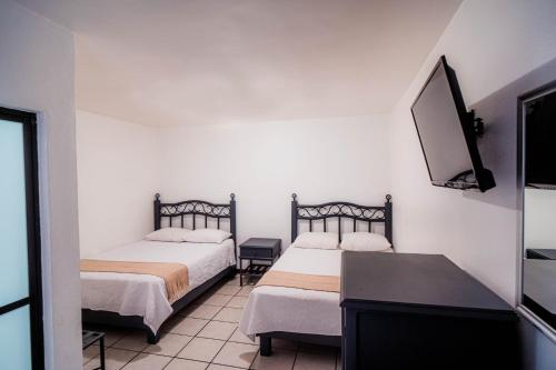 two beds in a room with a tv and a table at Marqués Oaxaca - Hotel in Oaxaca City
