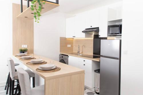 Il comprend une cuisine équipée d'un réfrigérateur et d'une table avec des chaises. dans l'établissement Appartement Moderne et Tropical 15 min Paris, à Juvisy-sur-Orge