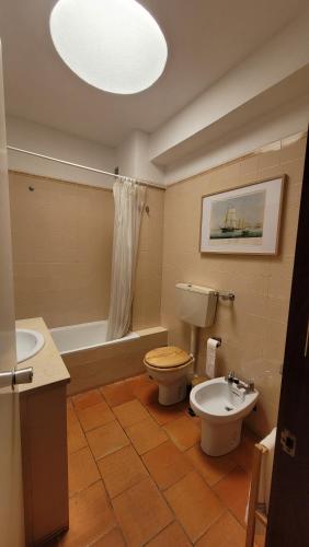 La salle de bains est pourvue de toilettes, d'un lavabo et d'une baignoire. dans l'établissement Casa Amarela _ Sesimbra, à Sesimbra
