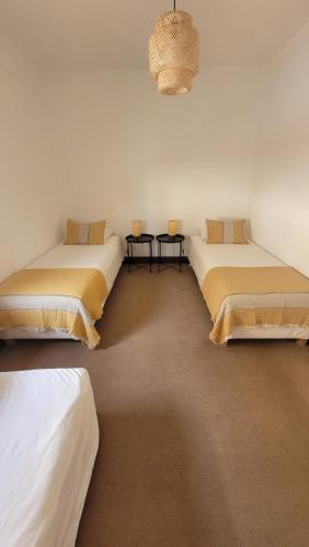 a room with three beds and a chandelier at Casa Amarela _ Sesimbra in Sesimbra