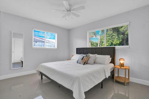 a white bedroom with a bed and two windows at Outdoor Paradise in Fort Lauderdale