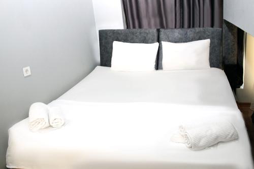 um quarto com uma cama com lençóis brancos e almofadas em Avist Hotel Avcılar em Avcılar