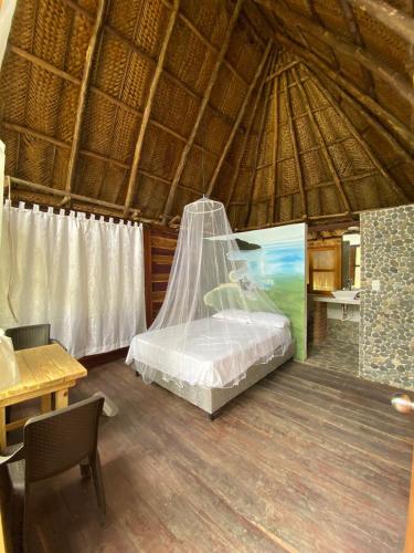 um quarto com uma cama numa cabana de palha em Ecohab - Sierra Nevada em Santa Marta