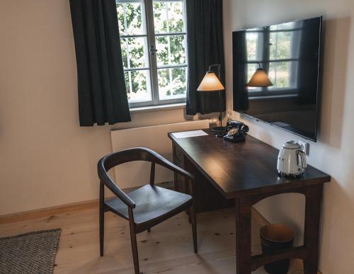 einen Schreibtisch mit einem Stuhl neben einem Fenster in der Unterkunft Gasthof Zantl in Bad Tölz