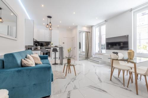 un salon avec un canapé bleu et une table dans l'établissement LB Vacation Rentals I Renovated Apt Minutes from Beach - Palais - 30m2 Terrace, à Cannes