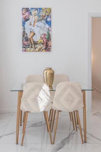 une table en verre avec deux chaises et un tableau sur le mur dans l'établissement LB Vacation Rentals I Renovated Apt Minutes from Beach - Palais - 30m2 Terrace, à Cannes