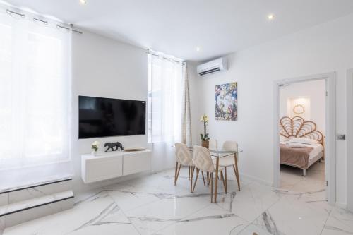 un salon blanc avec une télévision et une table dans l'établissement LB Vacation Rentals I Renovated Apt Minutes from Beach - Palais - 30m2 Terrace, à Cannes