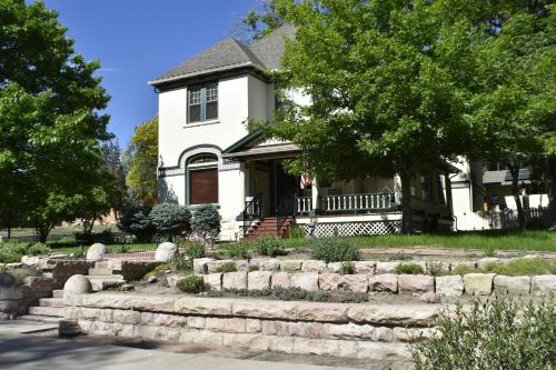 a white house with a stone wall in front of it at Downen House Bed & Breakfast in Pueblo