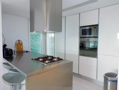 a kitchen with a counter with a stove and a microwave at Modern seafront apartment in Limassol