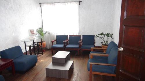 a living room with blue chairs and a table at Hostal prado colonial in Medellín