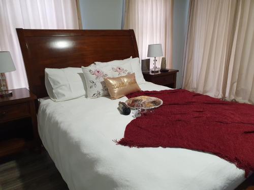 a bed with a red blanket and a plate on it at Charis on Beaumont in Margate