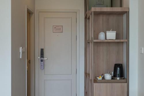 a white door in a room with a shelf at Wellington Hotel Prachuapkhirikhan in Ban Nong Bua