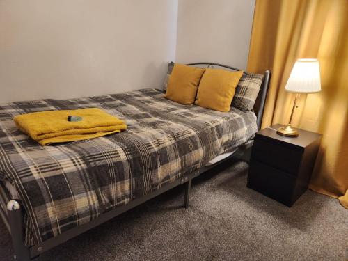 um quarto com uma cama com um cobertor amarelo em Home away from Home em Woolwich