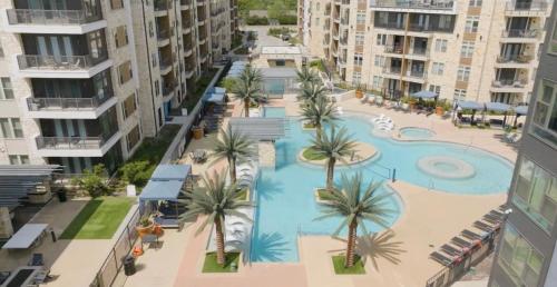 an aerial view of a pool with palm trees and buildings at 1 BR w Balcony View Resort Pool Free Parking in Addison