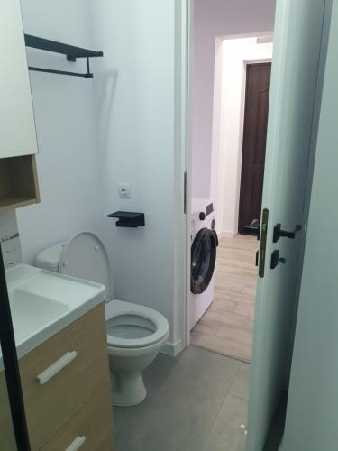 La salle de bains est pourvue de toilettes blanches et d'un lavabo. dans l'établissement Cozy Studio Onesti, à Onești