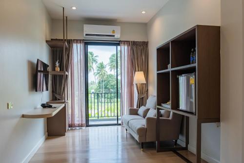 a living room with a couch and a large window at Wellington Hotel Prachuapkhirikhan in Ban Nong Bua