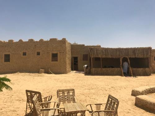 a group of chairs and tables in front of a building at Nashdeen Eco Lodge in Siwa