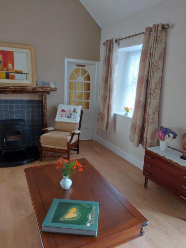 a living room with a fireplace and a table at Harmony Haven Cottage in Foxford