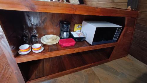a shelf with a microwave and plates on it at Chalé Capivari Esmeralda in Campos do Jordão