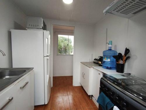 eine Küche mit weißen Schränken und einem weißen Kühlschrank in der Unterkunft Lodge Sol De Cáhuil in Pichilemu