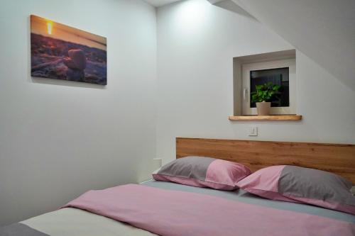 a bedroom with a bed with pink and grey pillows at Apartman Tilia in Ravna Gora