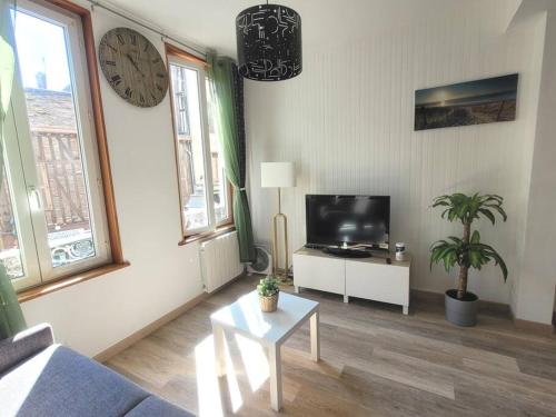 sala de estar con TV y reloj en la pared en Le Paséo, en Troyes