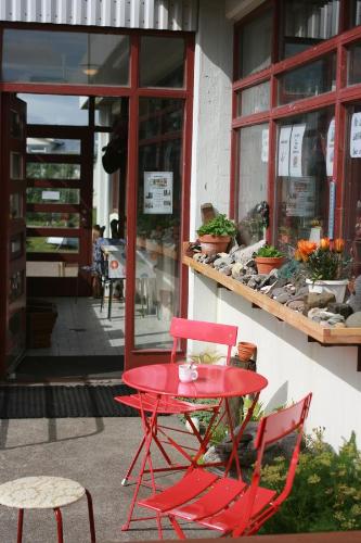 a red table and chairs in front of a store at Guesthouse Langafit in Laugarbakki
