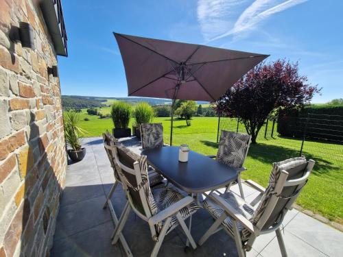 a table and chairs with an umbrella on a patio at Ferienwohnung Kessler's Eifeldomizil in Auw