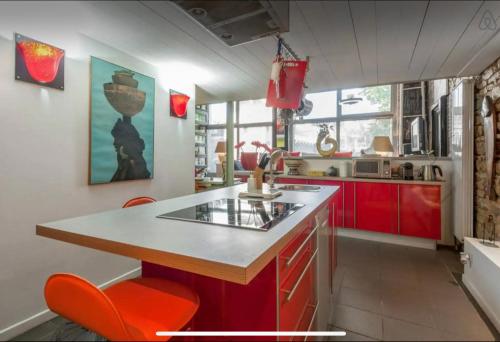 une cuisine avec des armoires rouges et un comptoir avec des chaises orange dans l'établissement Loft sur saône, à Lyon