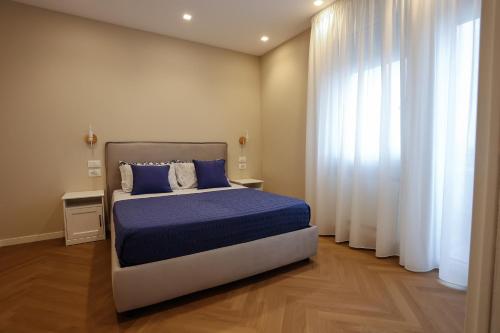 una camera da letto con letto con lenzuola e tende blu di T&L-Home a Reggio di Calabria