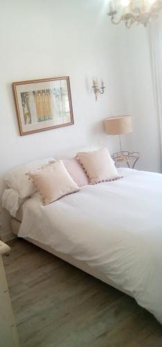 una camera da letto con un grande letto bianco con cuscini rosa di The bungalow a Saintes