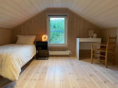 1 dormitorio con cama, ventana y escritorio en Flott nyere hytte med sjøutsikt., en Risør