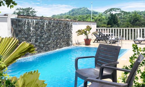 una piscina con 2 sillas y una fuente en HOTEL AMAZON GREEN, en Puerto Misahuallí