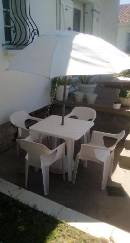 un tavolo bianco con sedie e ombrellone di The bungalow a Saintes