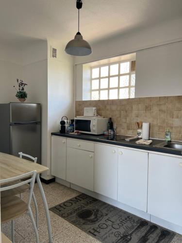 une cuisine avec des armoires blanches et un réfrigérateur en acier inoxydable dans l'établissement Studio avec balcon donnant sur les Arènes d’Arles, à Arles