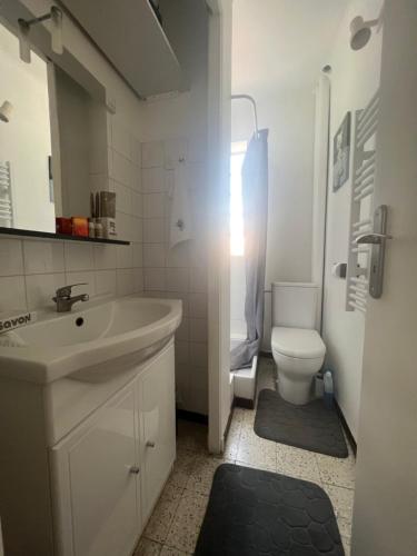 uma casa de banho branca com um lavatório e um WC em Studio avec balcon donnant sur les Arènes d’Arles em Arles