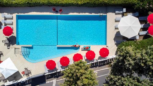 uma vista sobre uma piscina com cadeiras vermelhas e guarda-sóis em Hotel Ines em Cattolica
