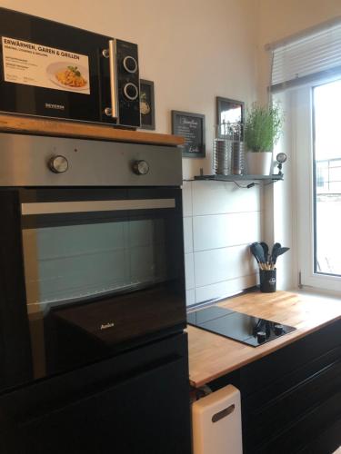 a kitchen with a microwave on top of a stove at Grüne Oase mit Balkon I EG in Duisburg